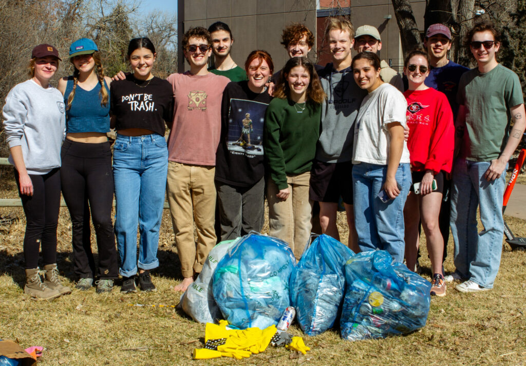 A group of people stand behind their bags of trash collected during the clean-up.