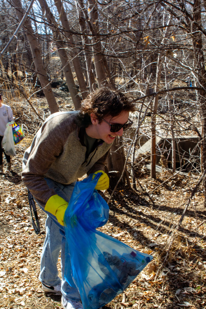 A man holds a trash bag outside at a park during a clean-up.