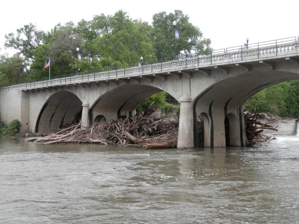 Large amounts of wood clogging the underneath of a bridge