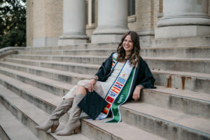 A woman sits on concrete stairs and smiles.